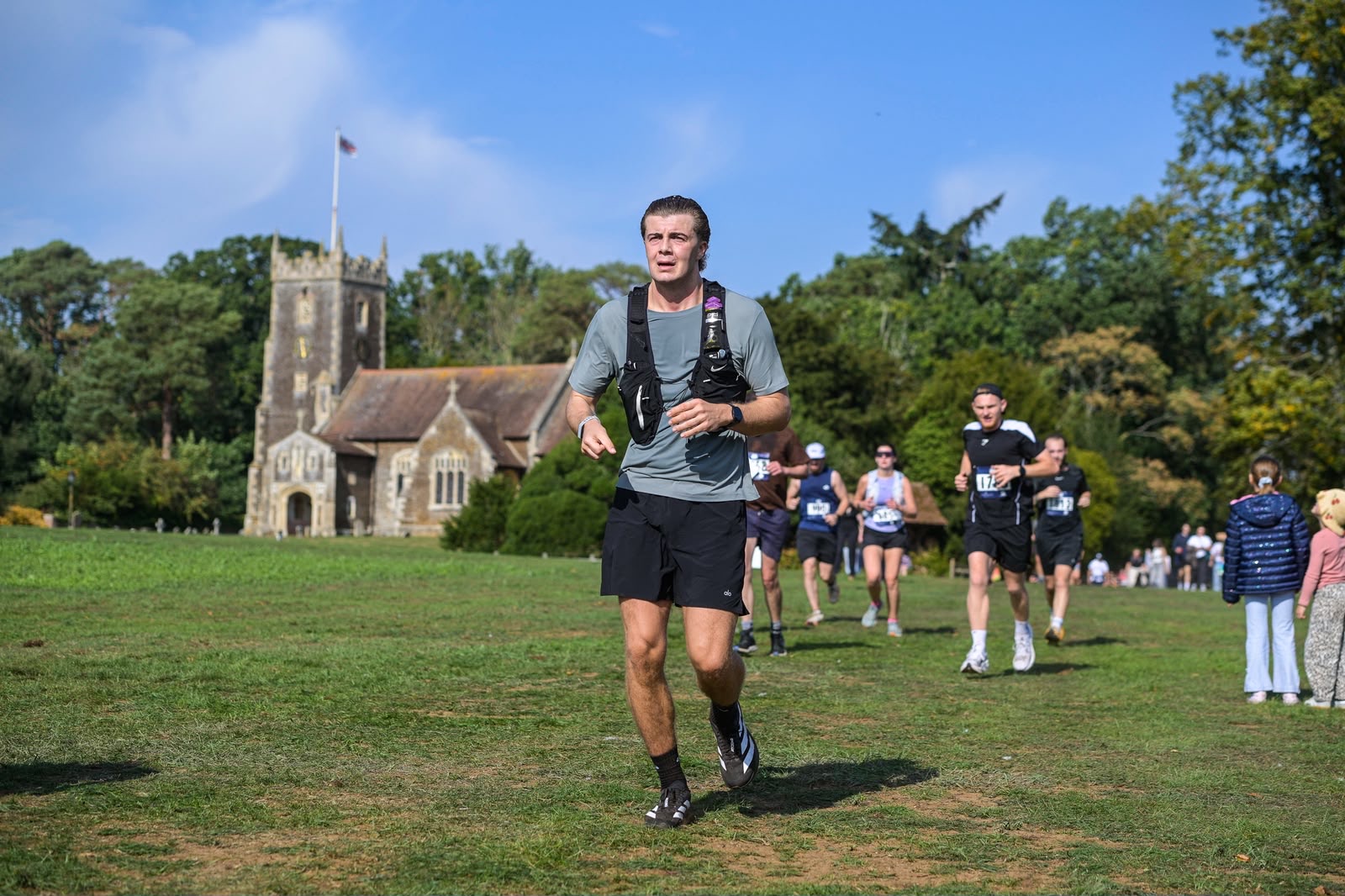 Luke running across the grass in front of the church on the Sandringham Estate during the half marathon