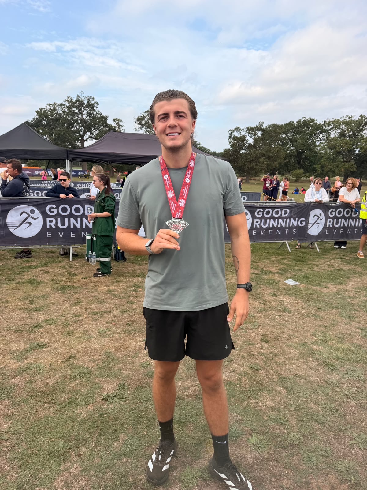 Luke from Prestige Roof smiling and holding up his Sandringham Half Marathon finisher medal