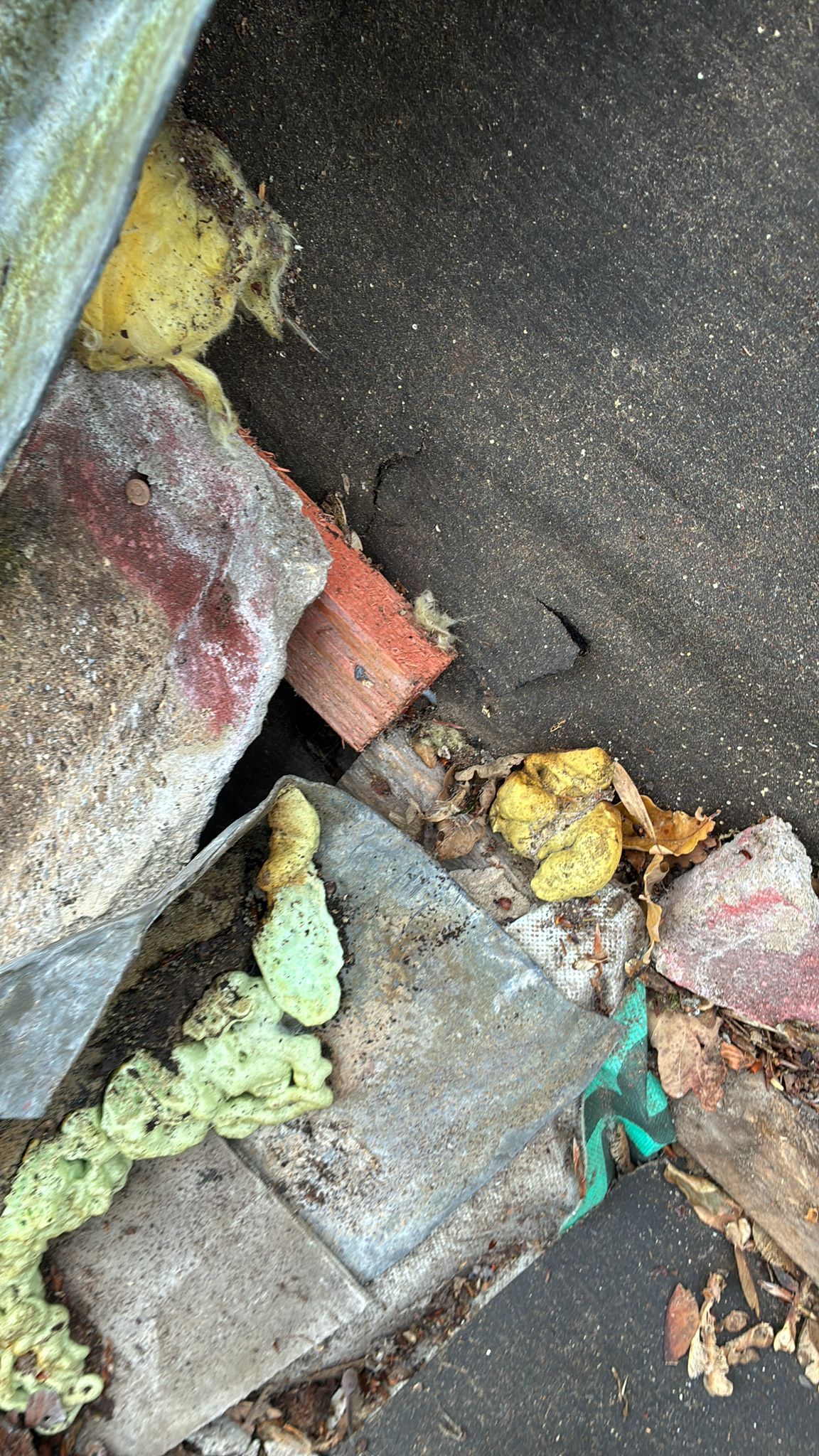 Accumulated debris, broken mortar and deteriorated materials around the chimney base in Roughton