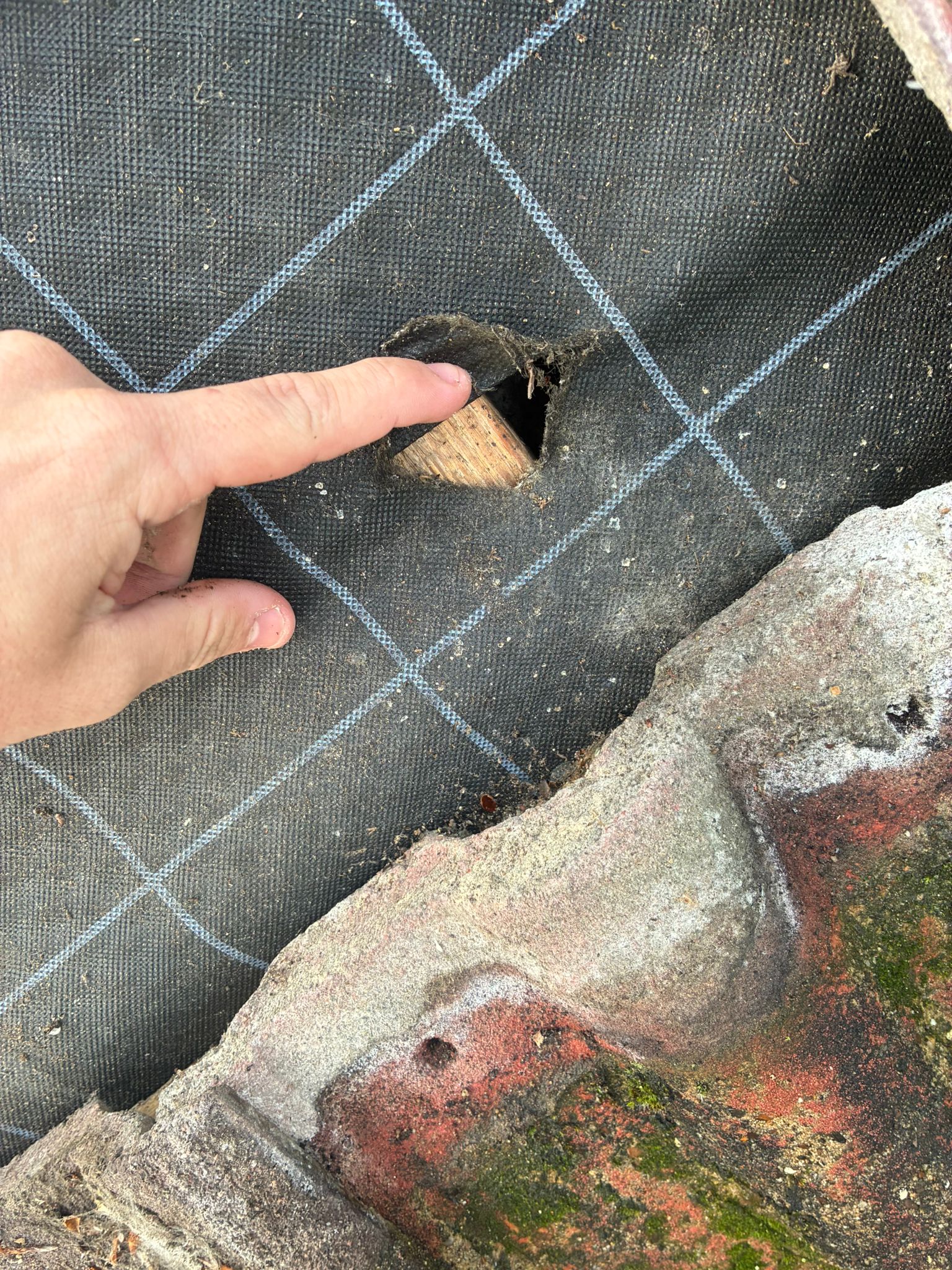 Close-up showing a hole torn through the roof membrane near the chimney stack in Roughton
