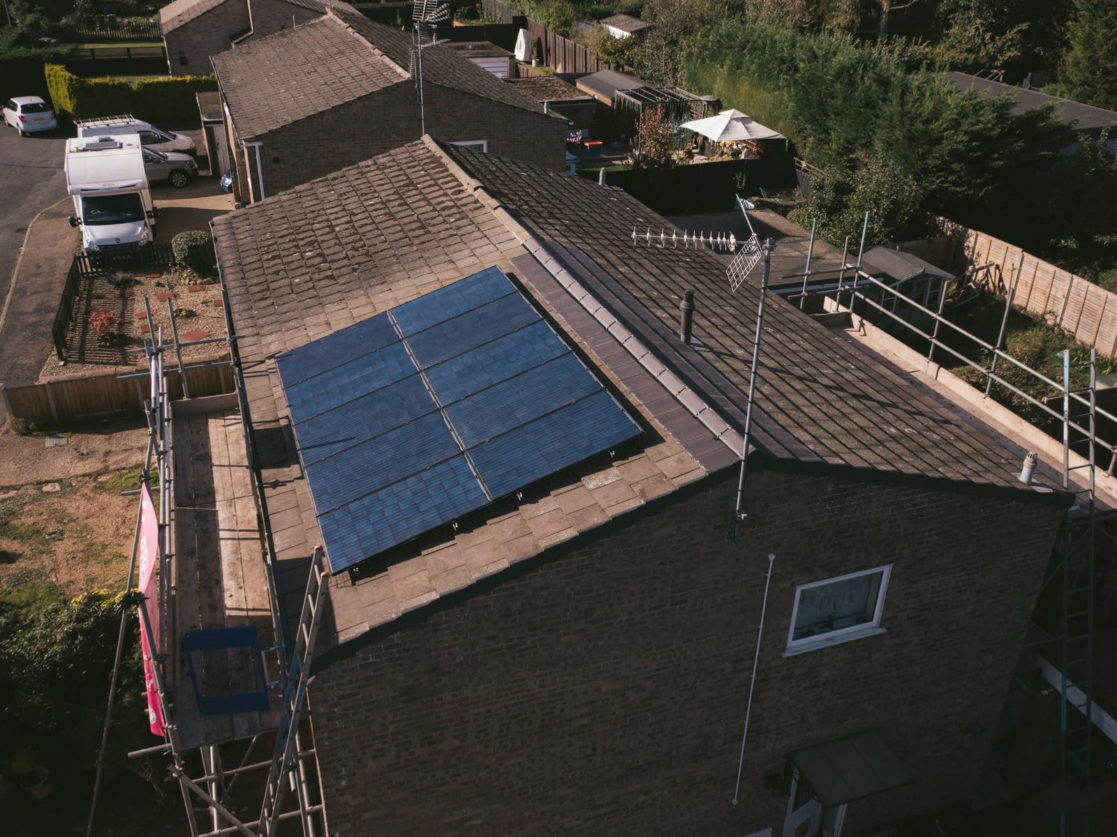 Aerial view of the original concrete tile roof with solar panels and scaffold going up