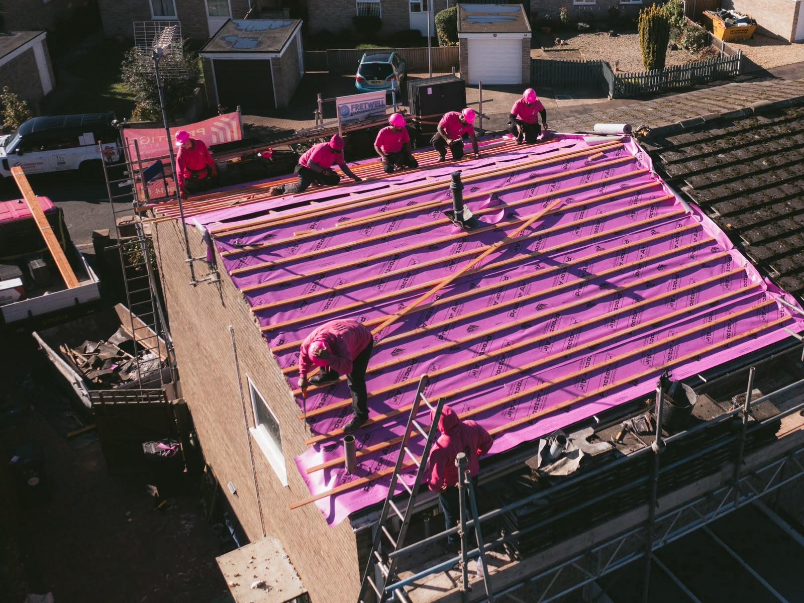 The Prestige Roof team in pink hard hats fixing treated battens over the new membrane