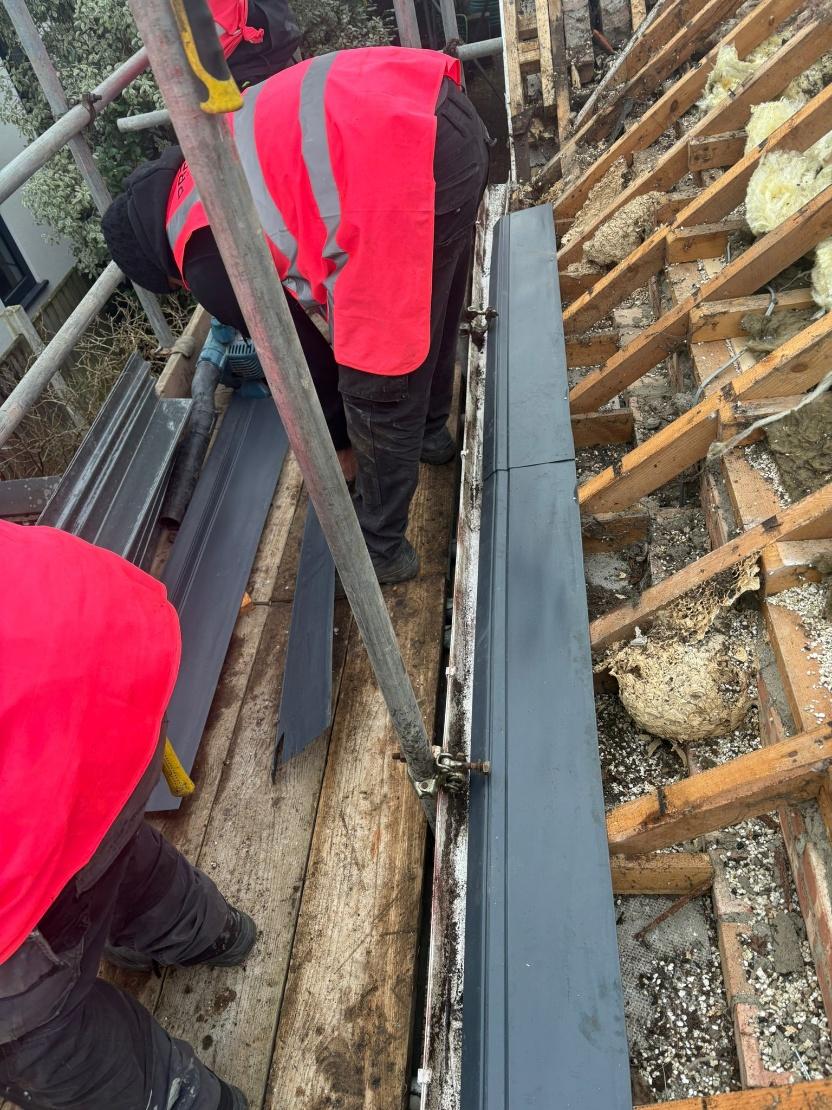 Roofers installing new black eaves support trays along the roof perimeter